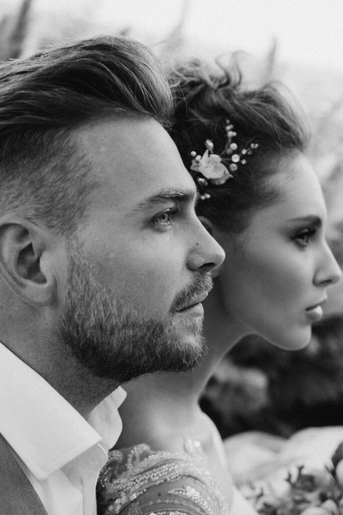 Together, Toward Everything Ahead Close-up black-and-white portrait of a bride and groom looking forward with calm intensity.<br />